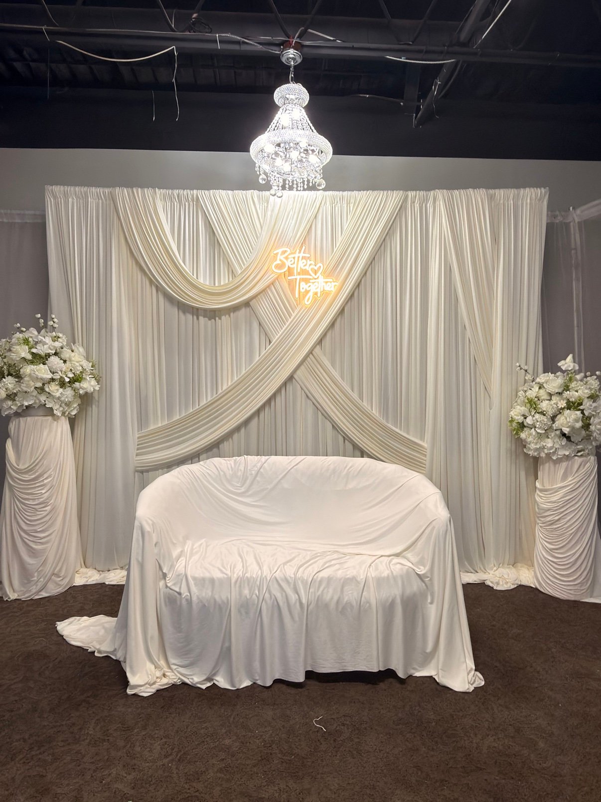 White draped backdrop with chandelier by Penbaga Events