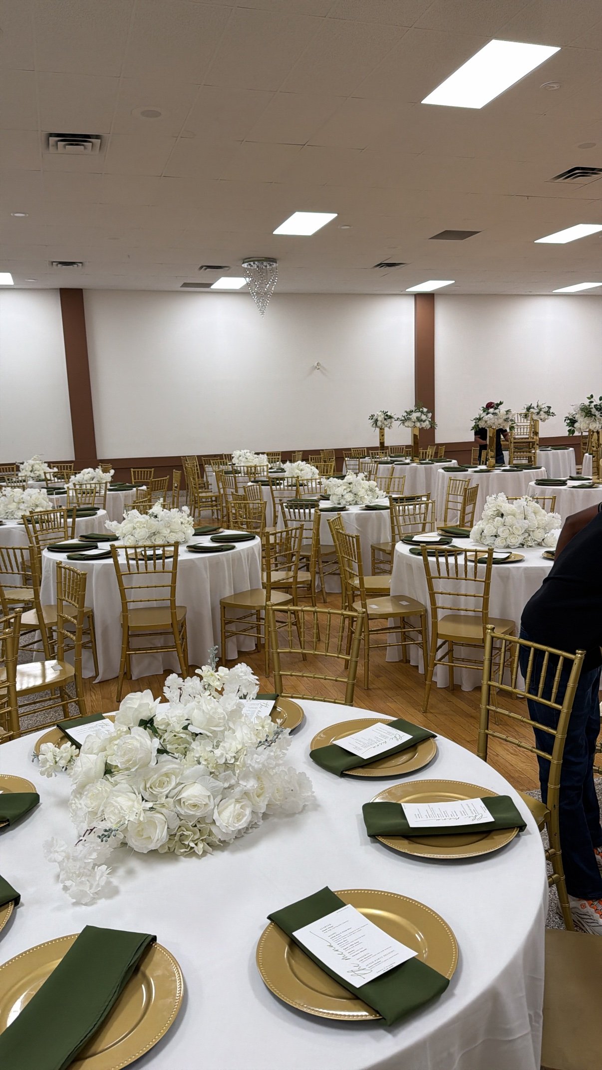Full banquet hall with draped tables and chandeliers by Penbaga Events